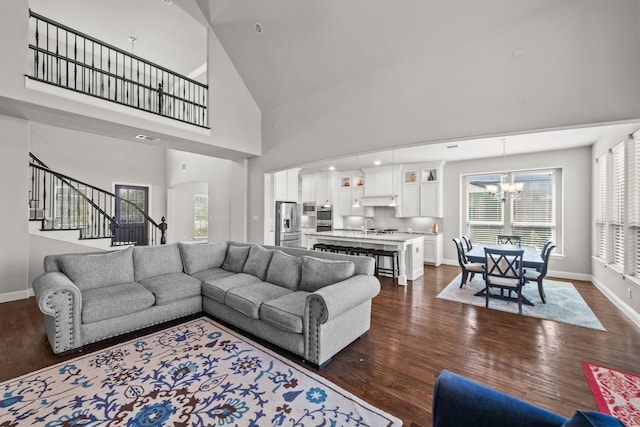 living room with a high ceiling, sink, dark wood-type flooring, and an inviting chandelier