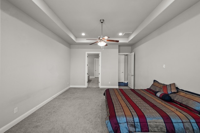 unfurnished bedroom with ceiling fan, a raised ceiling, and carpet flooring