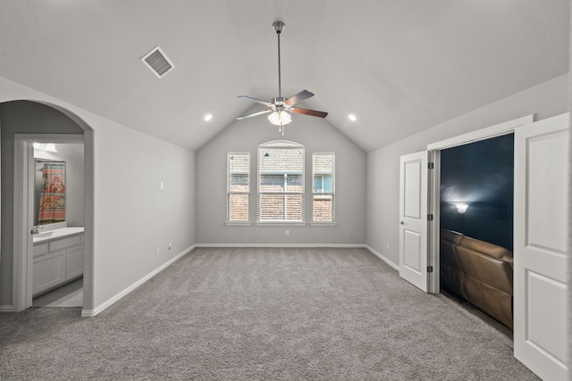 unfurnished living room featuring light colored carpet, vaulted ceiling, and ceiling fan