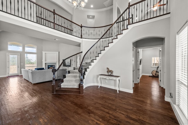 interior space featuring a towering ceiling, a notable chandelier, dark wood-type flooring, and ornamental molding