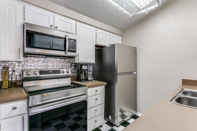 kitchen featuring sink, white cabinetry, a textured ceiling, appliances with stainless steel finishes, and decorative backsplash