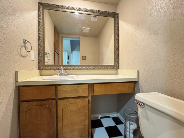 bathroom featuring vanity, toilet, and a textured ceiling