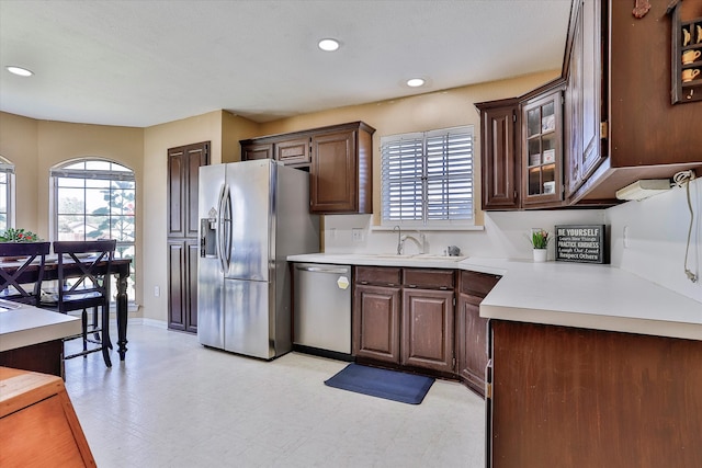 kitchen featuring sink, stainless steel appliances, light tile patterned flooring, and dark brown cabinets