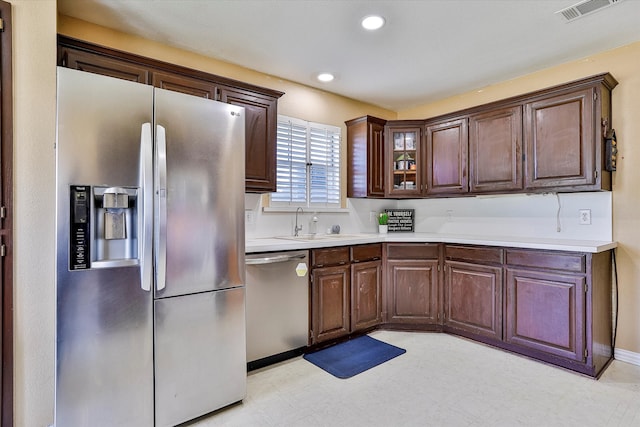 kitchen with sink, stainless steel appliances, light tile patterned floors, and dark brown cabinets