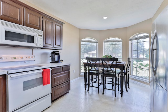 kitchen featuring white appliances, light tile patterned flooring, and dark brown cabinetry