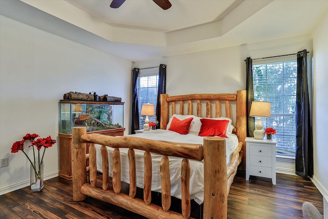 bedroom featuring ceiling fan, a raised ceiling, and dark hardwood / wood-style floors