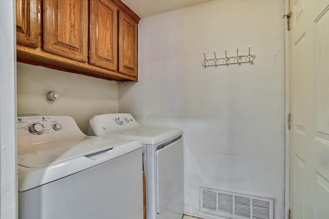 laundry area featuring washer and clothes dryer and cabinets