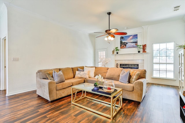 living room featuring ceiling fan, hardwood / wood-style floors, a tile fireplace, and ornamental molding