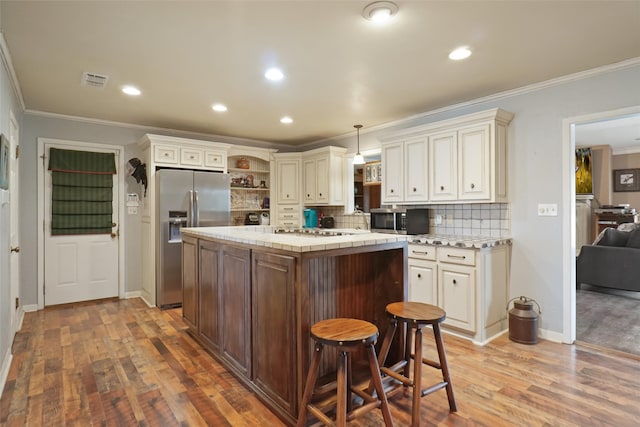 kitchen featuring backsplash, stainless steel appliances, decorative light fixtures, ornamental molding, and hardwood / wood-style flooring