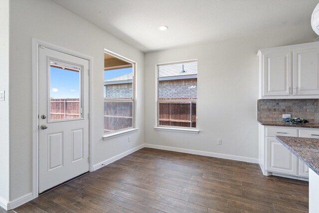 unfurnished dining area featuring dark wood-type flooring and a healthy amount of sunlight