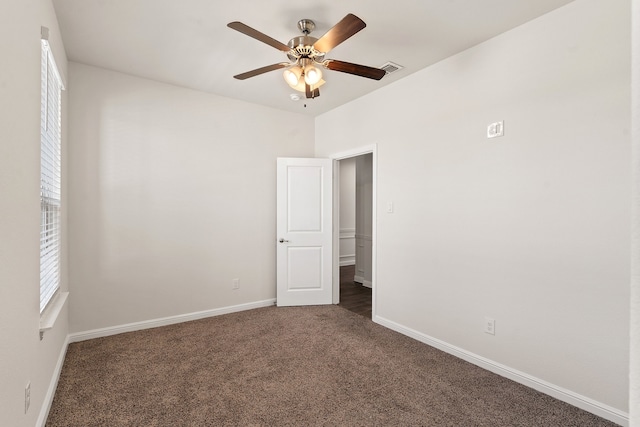 empty room featuring ceiling fan and dark carpet