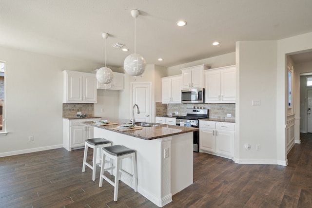 kitchen with sink, appliances with stainless steel finishes, white cabinetry, and an island with sink