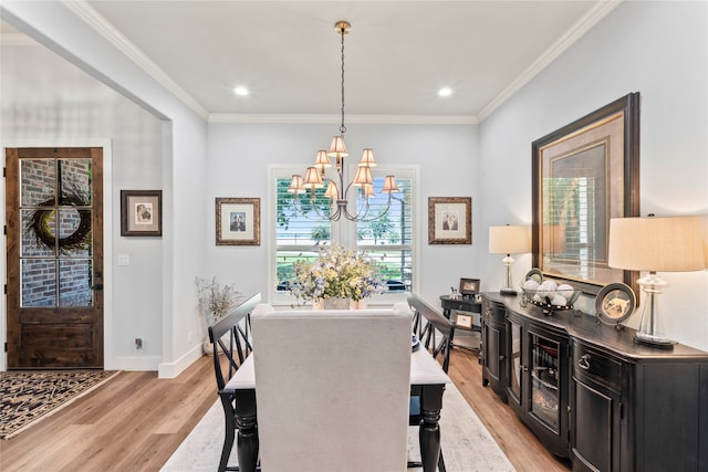 dining room featuring light hardwood / wood-style floors, crown molding, and an inviting chandelier