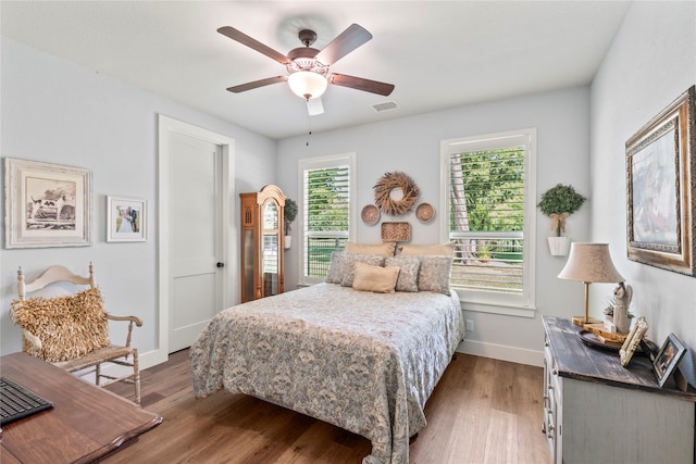 bedroom with hardwood / wood-style floors, ceiling fan, and multiple windows