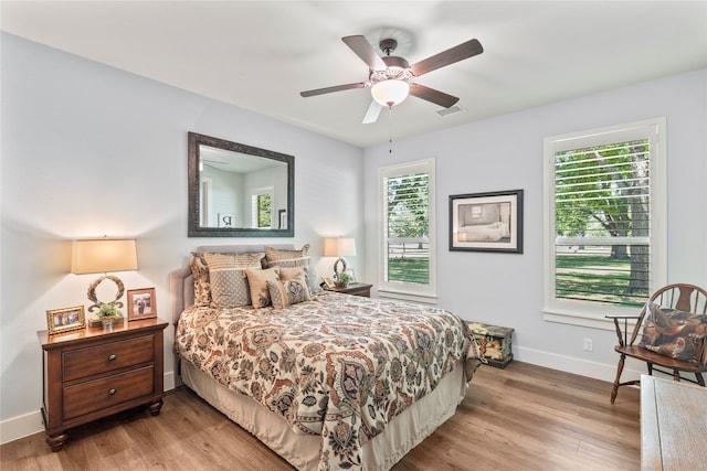 bedroom with light hardwood / wood-style floors, ceiling fan, and multiple windows