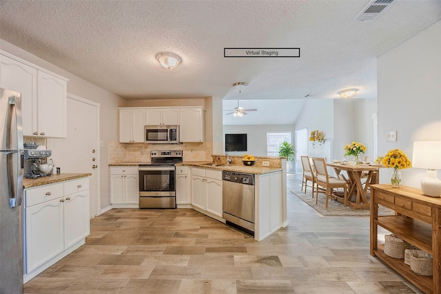 kitchen featuring ceiling fan, kitchen peninsula, a textured ceiling, white cabinetry, and stainless steel appliances