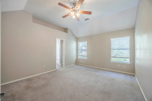 carpeted spare room with ceiling fan, a textured ceiling, vaulted ceiling, and a wealth of natural light