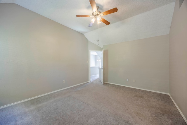 unfurnished room with vaulted ceiling, ceiling fan, carpet flooring, and a textured ceiling