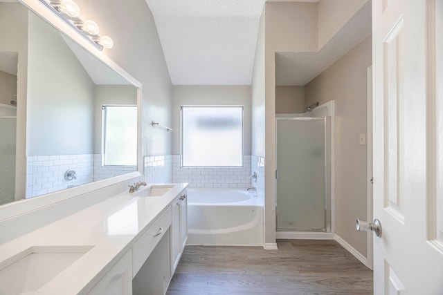 bathroom featuring independent shower and bath, hardwood / wood-style flooring, vanity, and vaulted ceiling