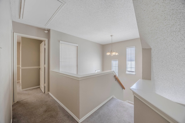 hallway featuring light colored carpet and a textured ceiling