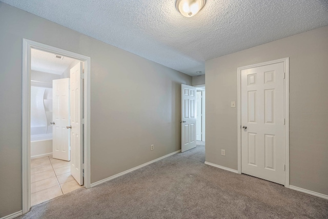 unfurnished bedroom with light carpet, a textured ceiling, and connected bathroom