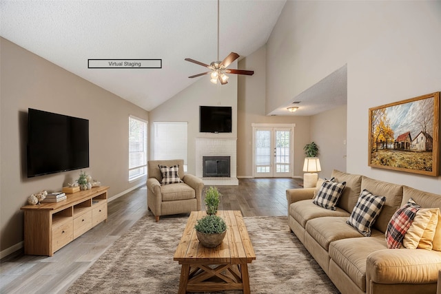 living room with a brick fireplace, high vaulted ceiling, a textured ceiling, ceiling fan, and hardwood / wood-style floors