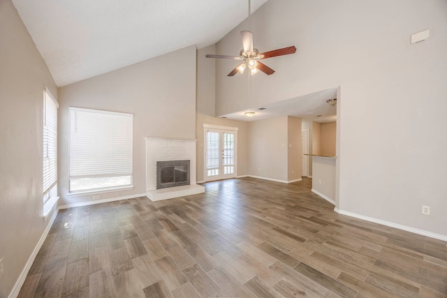 unfurnished living room featuring wood-type flooring, ceiling fan, high vaulted ceiling, and a wealth of natural light