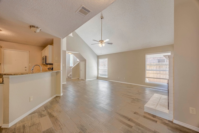 interior space with a textured ceiling, light hardwood / wood-style floors, ceiling fan, and plenty of natural light