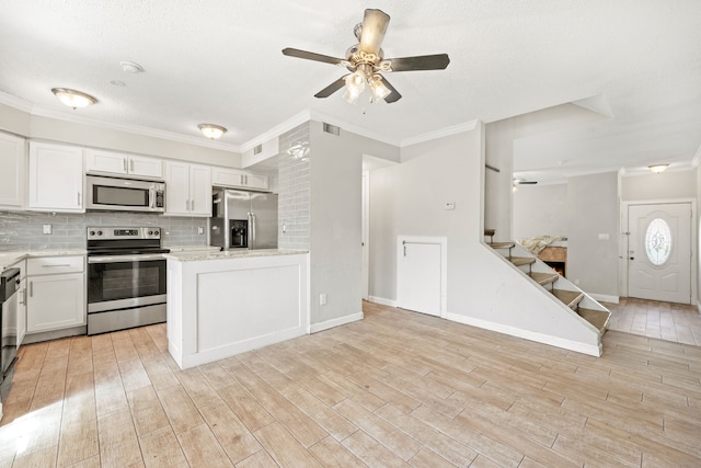 kitchen featuring backsplash, ornamental molding, white cabinetry, ceiling fan, and stainless steel appliances