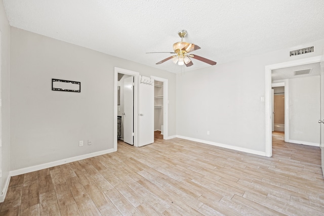 unfurnished bedroom with ceiling fan, a closet, a spacious closet, and light hardwood / wood-style flooring