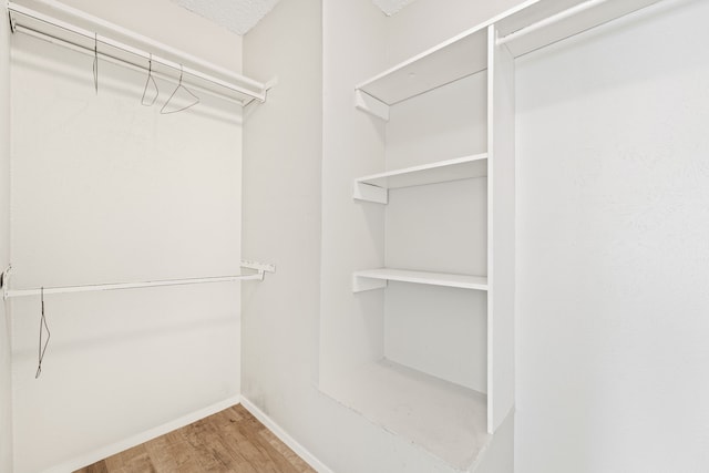 walk in closet with light hardwood / wood-style flooring