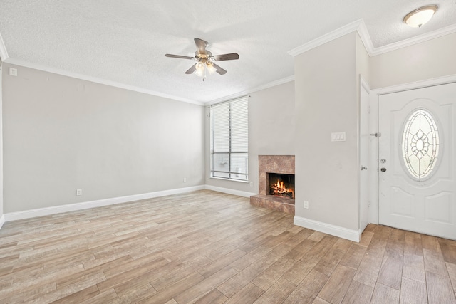 foyer featuring a fireplace, ceiling fan, crown molding, and light hardwood / wood-style flooring