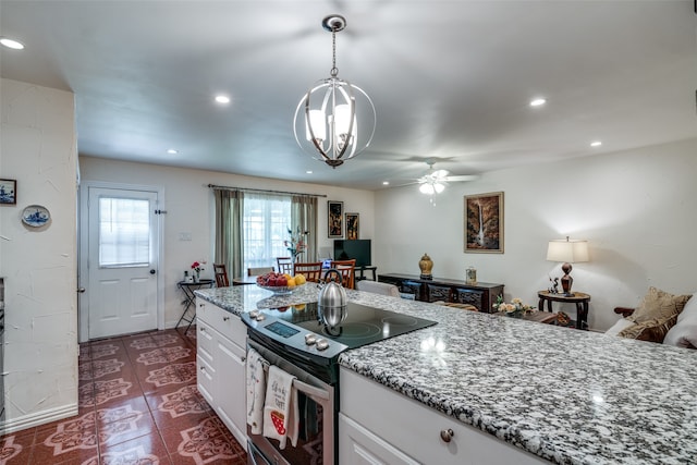 kitchen featuring decorative light fixtures, dark tile patterned flooring, ceiling fan with notable chandelier, electric stove, and white cabinetry