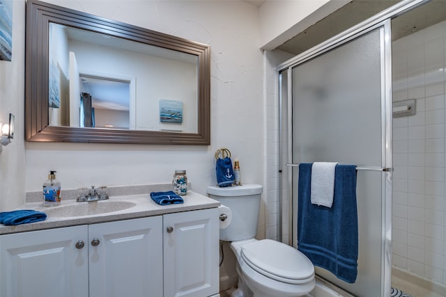 bathroom with a shower with shower door, vanity, and toilet