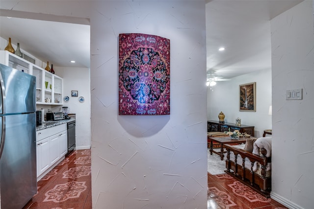 kitchen with white cabinetry, stainless steel refrigerator, stone countertops, black dishwasher, and ceiling fan