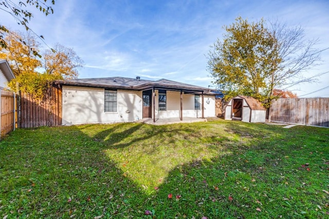 back of property with a yard, a storage unit, and a patio area