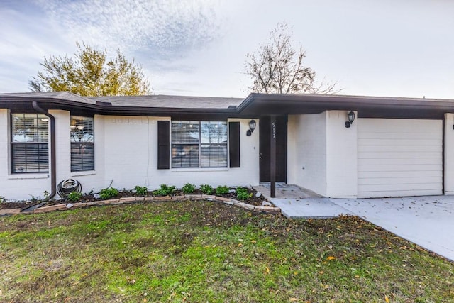 ranch-style house featuring a garage and a front lawn