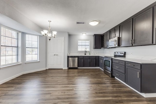 kitchen featuring a notable chandelier, dark hardwood / wood-style floors, decorative light fixtures, and appliances with stainless steel finishes