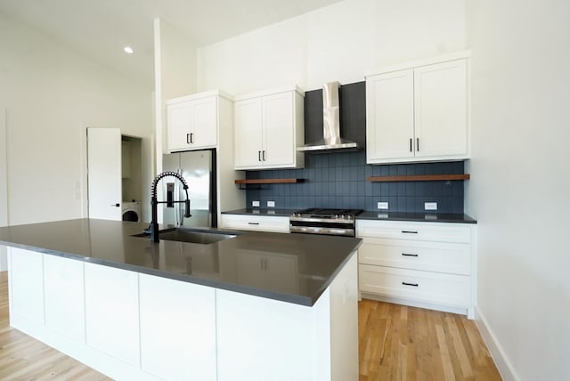 kitchen with stainless steel appliances, a kitchen island with sink, wall chimney exhaust hood, and sink