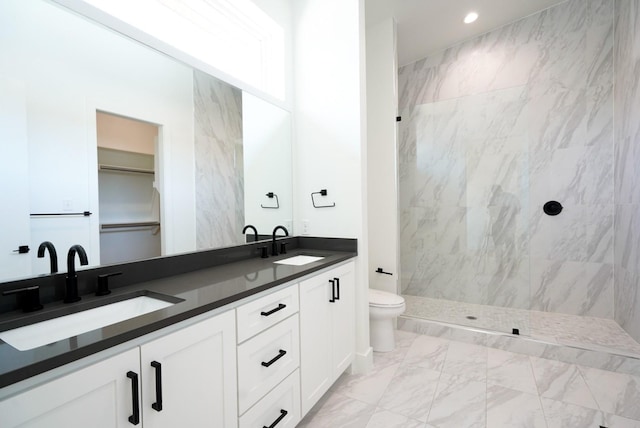 bathroom with vanity, toilet, and a tile shower