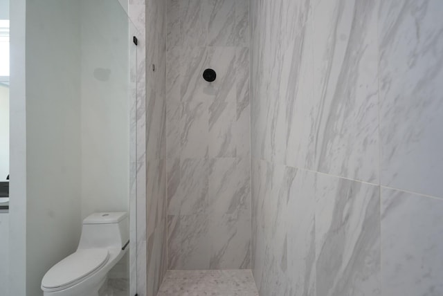 bathroom featuring a tile shower and toilet