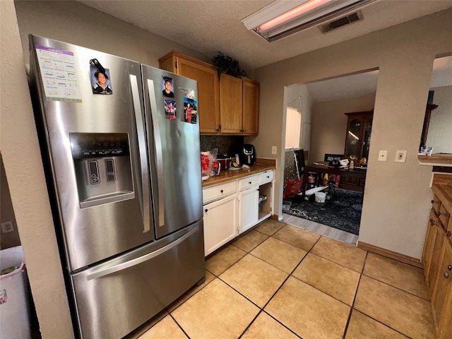 kitchen featuring light tile patterned floors, backsplash, and stainless steel fridge