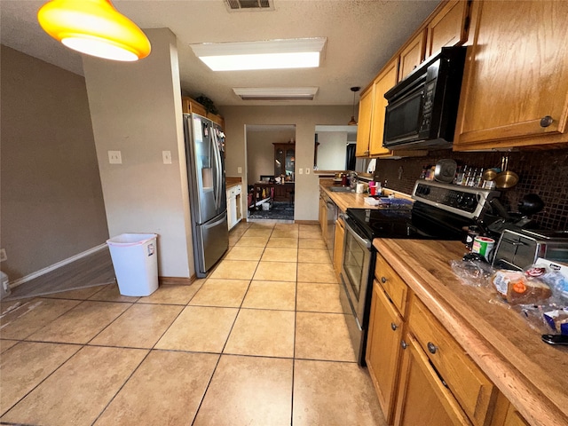 kitchen with backsplash, sink, light tile patterned floors, stainless steel appliances, and pendant lighting