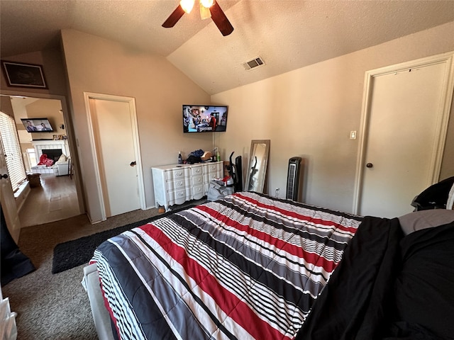 bedroom featuring ceiling fan, carpet flooring, vaulted ceiling, and a textured ceiling