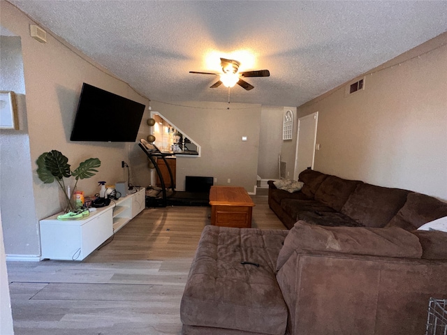 living room featuring ceiling fan, a textured ceiling, and wood-type flooring