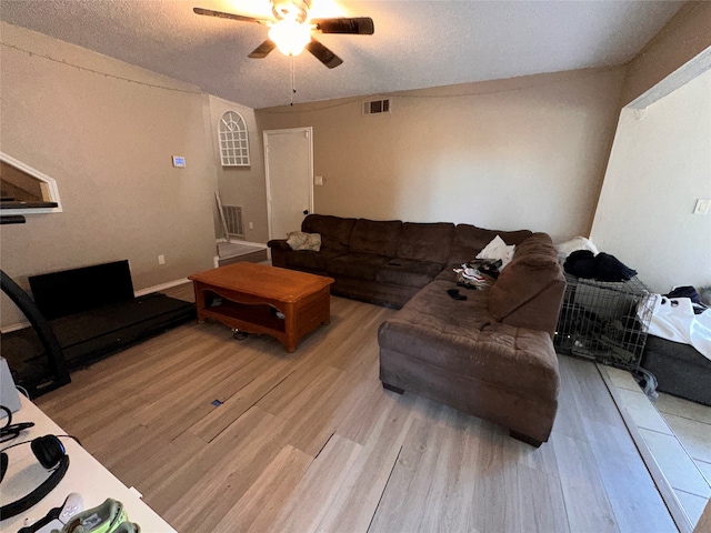 living room featuring ceiling fan, a textured ceiling, and light hardwood / wood-style floors