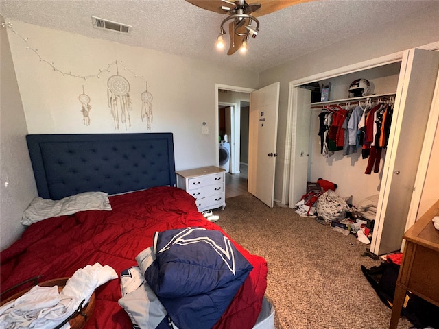 carpeted bedroom with a textured ceiling, a closet, ceiling fan, and washer / dryer