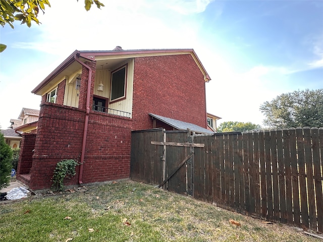 view of side of home featuring a balcony and a lawn