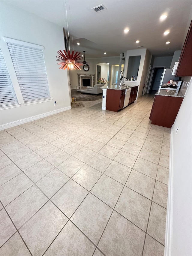 living room featuring recessed lighting, a fireplace with raised hearth, light tile patterned flooring, visible vents, and baseboards