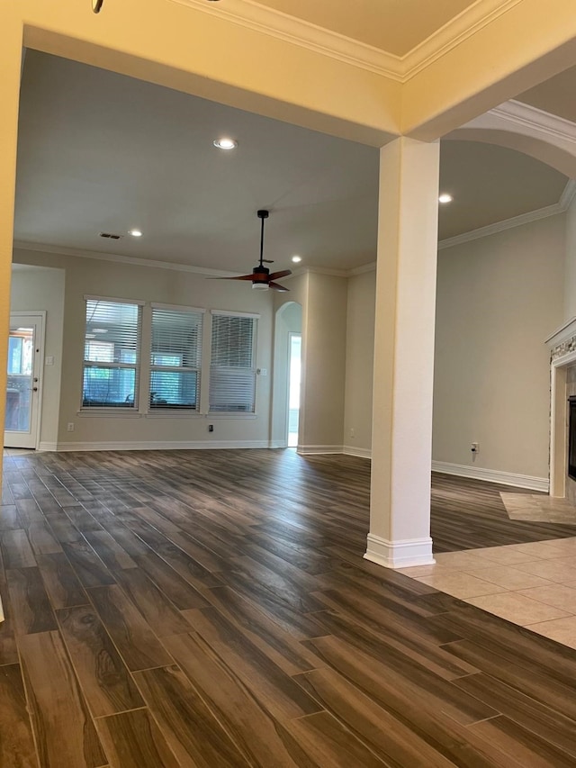 unfurnished living room with crown molding, arched walkways, dark wood-style flooring, recessed lighting, and a fireplace